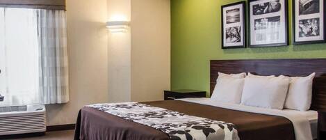 Quarto de hotel com cama, mesa de cabeceira, luminária na parede e quadros enquadrados.