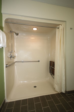 A walk-in shower with a grab bar, a shower curtain, and a tiled floor. - Sleep Inn Concord - Kannapolis (Concord)