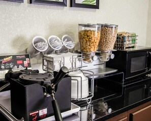 A kitchen with a waffle maker, paper towel dispenser, and cereal containers.