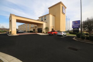 A Sleep Inn hotel with a large parking lot, a red pickup truck, and a sign indicating an indoor heated pool. - Sleep Inn Concord - Kannapolis (Concord)