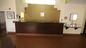 A reception desk with a sign indicating a sleep inn. There is a framed picture on the wall to the left and a shelf with items to the right. - Sleep Inn Concord - Kannapolis (Concord)
