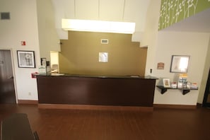 A reception desk with a sign indicating a sleep inn. There is a framed picture on the wall to the left and a shelf with items to the right. - Sleep Inn Concord - Kannapolis (Concord)
