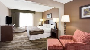Une chambre d’hôtel avec un lit, un bureau avec une télévision, une chaise et une lampe.