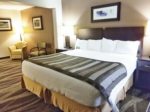 A hotel room with a large bed, a chair, a nightstand, and two wall-mounted lamps.