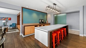 A modern kitchen with a bar area, wooden flooring, and a large island with bar stools. - MainStay Suites Greensboro (Greensboro)