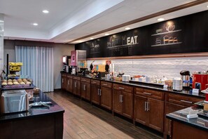 A hotel kitchen with a buffet setup, wooden cabinets, and a chalkboard menu.
