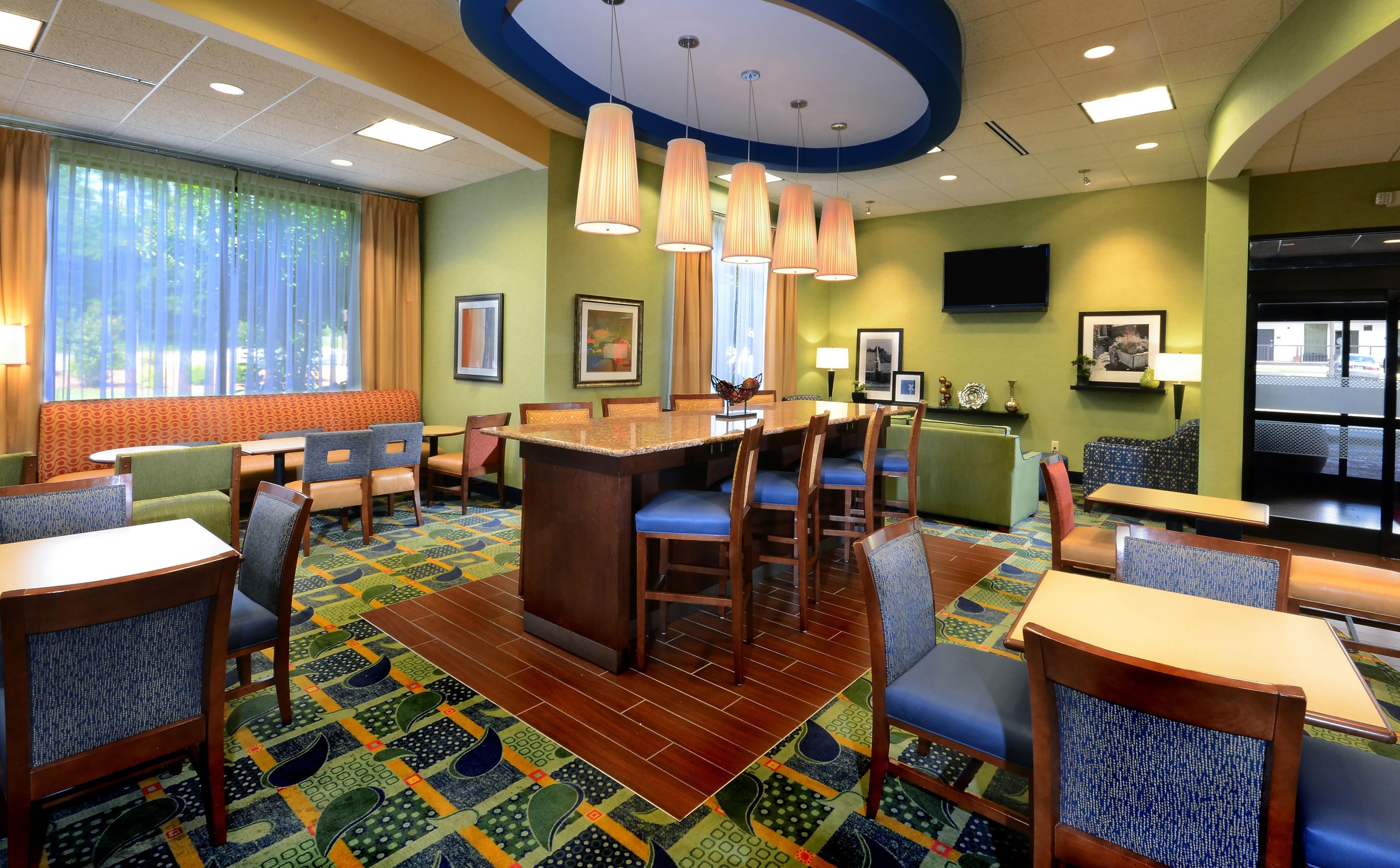 A hotel dining area with a long communal table, multiple booths, and chairs.