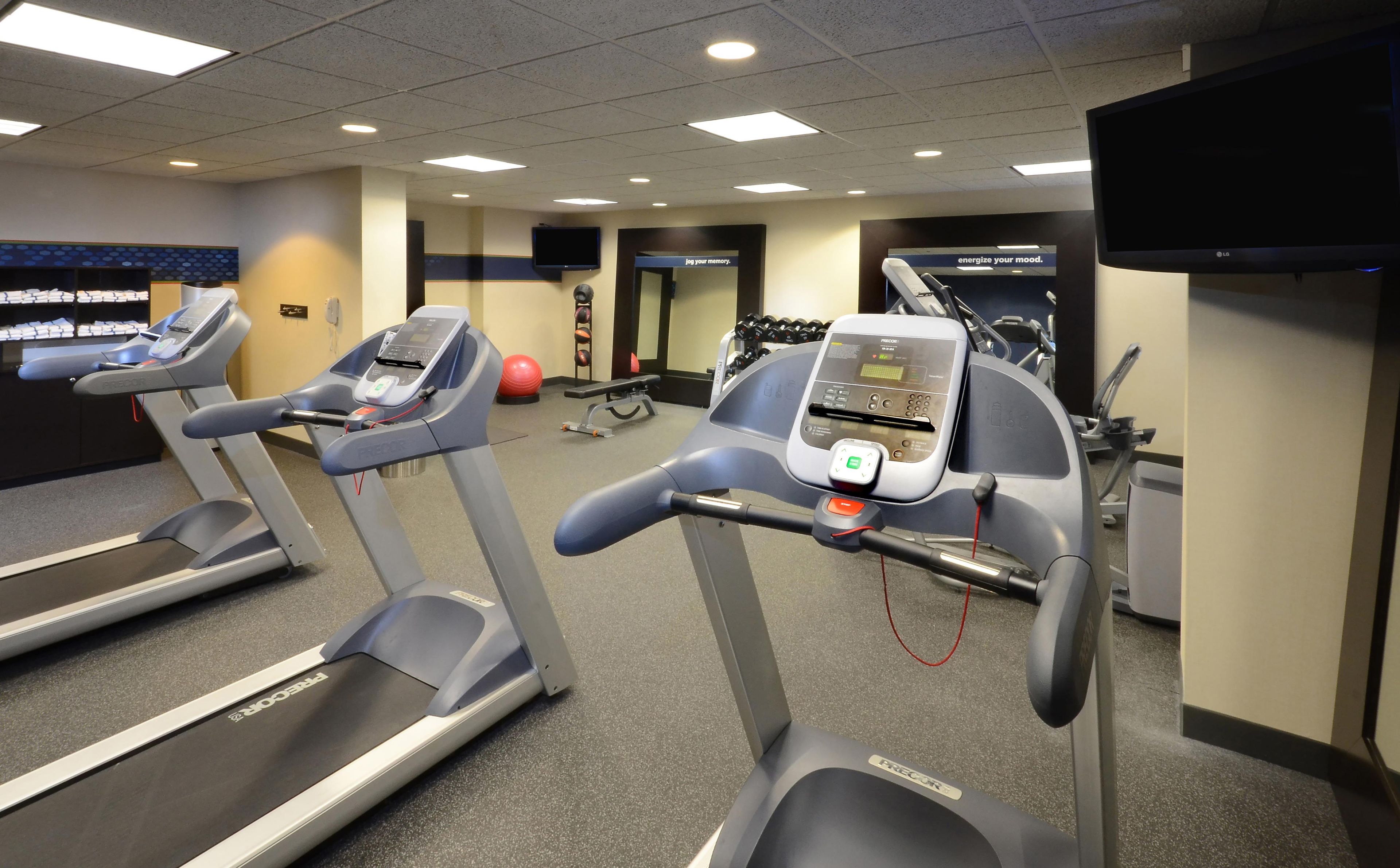A gym with treadmills, a stationary bike, and a wall-mounted TV.