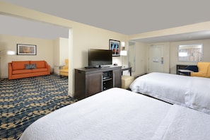 A hotel room with a sofa, a desk with a TV, a bed, and a small table. - Hampton Inn Roxboro (Roxboro)