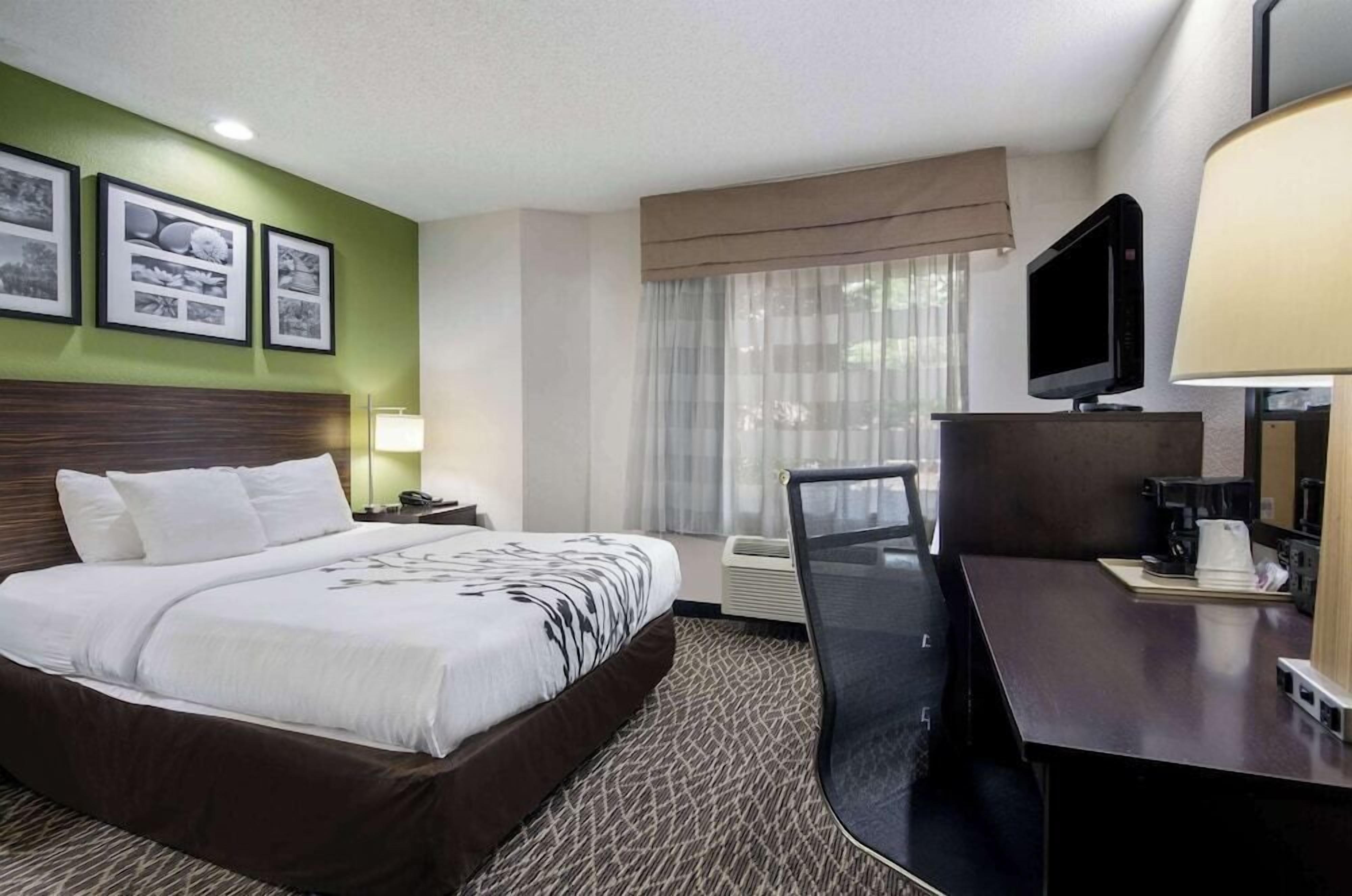 A hotel room with a bed, a desk, a television, and a window with curtains.
