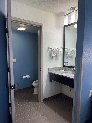 A bathroom with a toilet, a sink with a mirror, and towels hanging on a rack. - Sleep Inn Hanes Mall (Winston-Salem)
