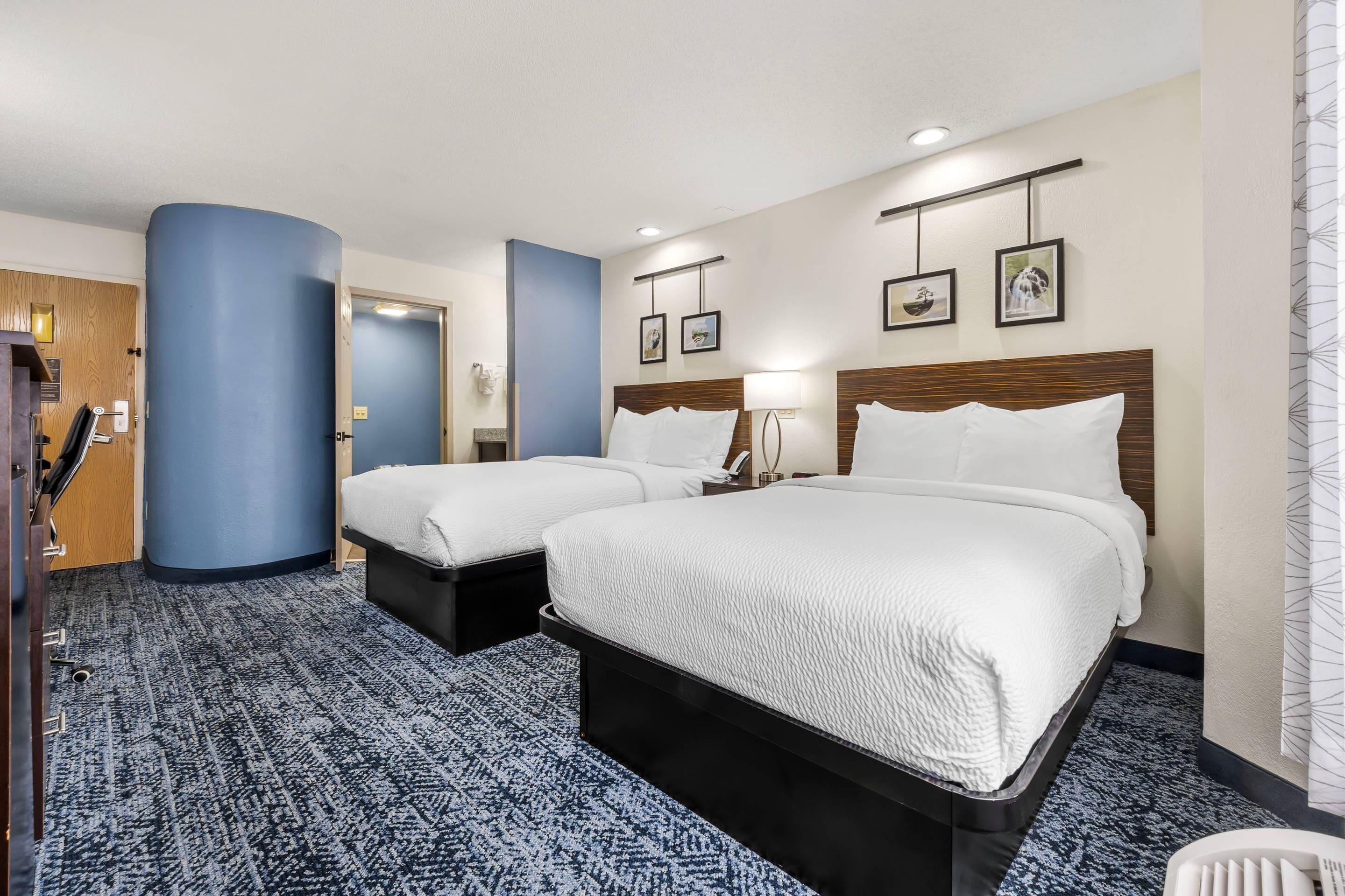 Ett hotellrum med två sängar, ett skrivbord och ett badrum.