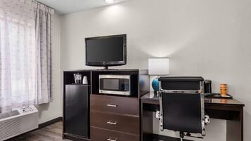 Habitación de hotel con televisión de pantalla plana, microondas, refrigerador minibar, escritorio con silla y calentador.