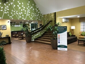 A hotel lobby with a staircase, a reception desk, and a dining area. - Sleep Inn Hanes Mall (Winston-Salem)