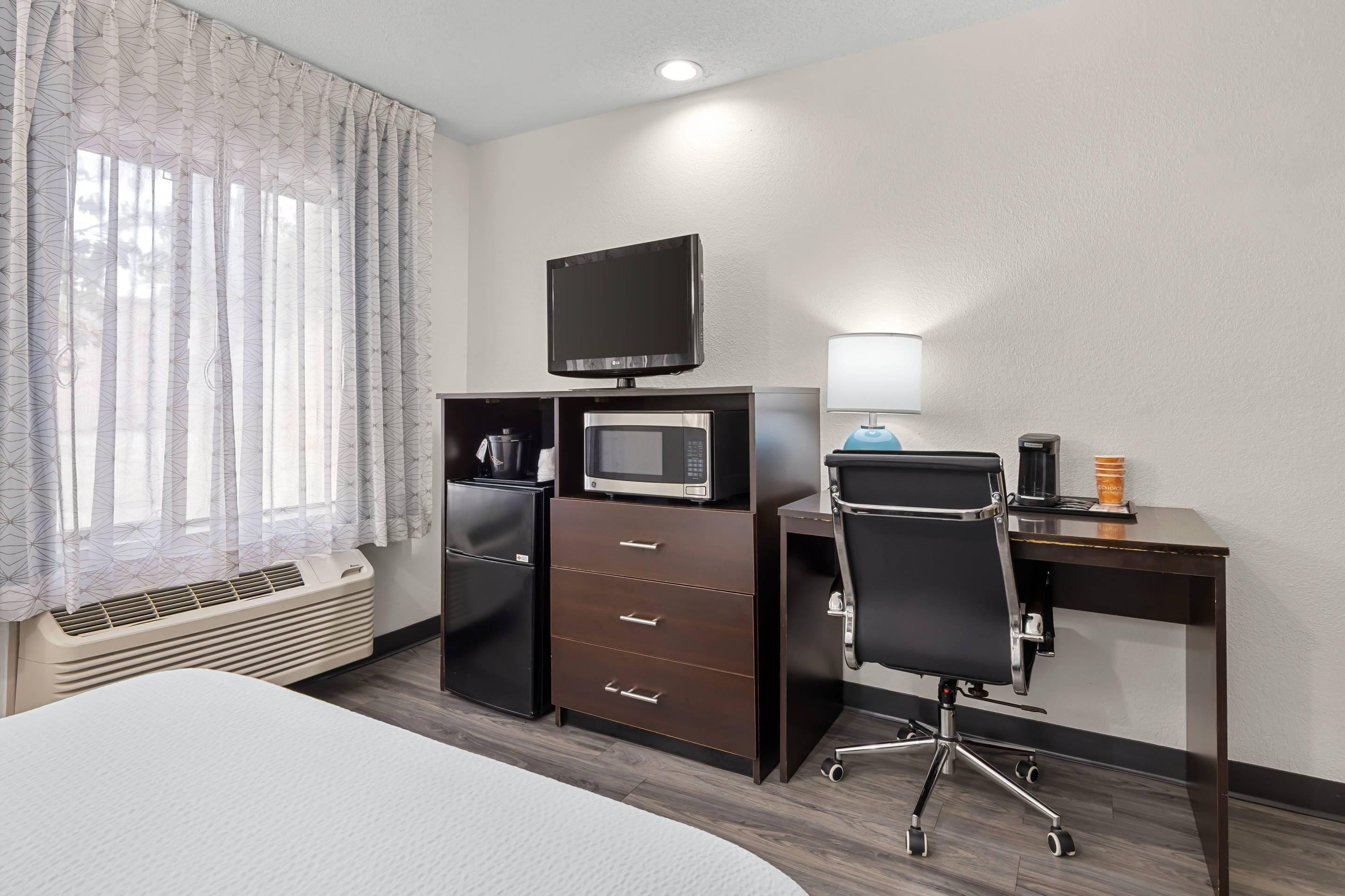Ein Hotelzimmer mit Bett, Schreibtisch mit Stuhl, Flachbildfernseher, Mikrowelle, Kaffeemaschine und Heizung.
