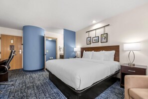 A hotel room with a large bed, a desk, a chair, and a bathroom visible through an open door. - Sleep Inn Hanes Mall (Winston-Salem)
