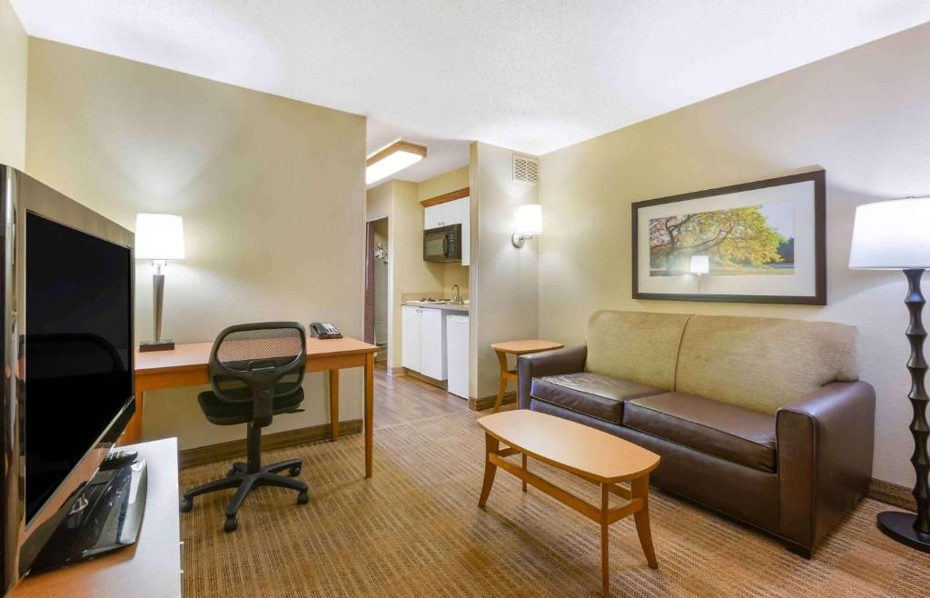 A hotel room with a desk, office chair, sofa, and a television.