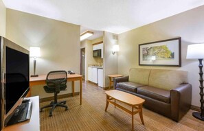 A hotel room with a desk, office chair, sofa, and a television. - Studio 6 Extended Stay Findlay Tiffin Avenue OH (Findlay)