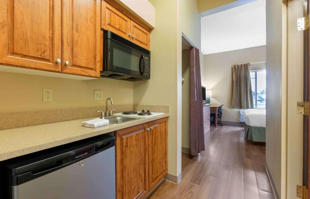 A compact kitchen with wooden cabinets, a built-in microwave, a dishwasher, and a sink.