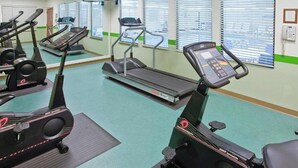 Une salle de sport équipée de tapis de course, de vélos d’appartement et d’appareils elliptiques.