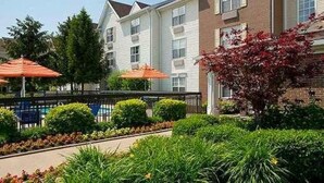 A row of townhouses with a swimming pool and outdoor umbrellas. - Towneplace Suites By Marriott Cleveland Westlake (Westlake)