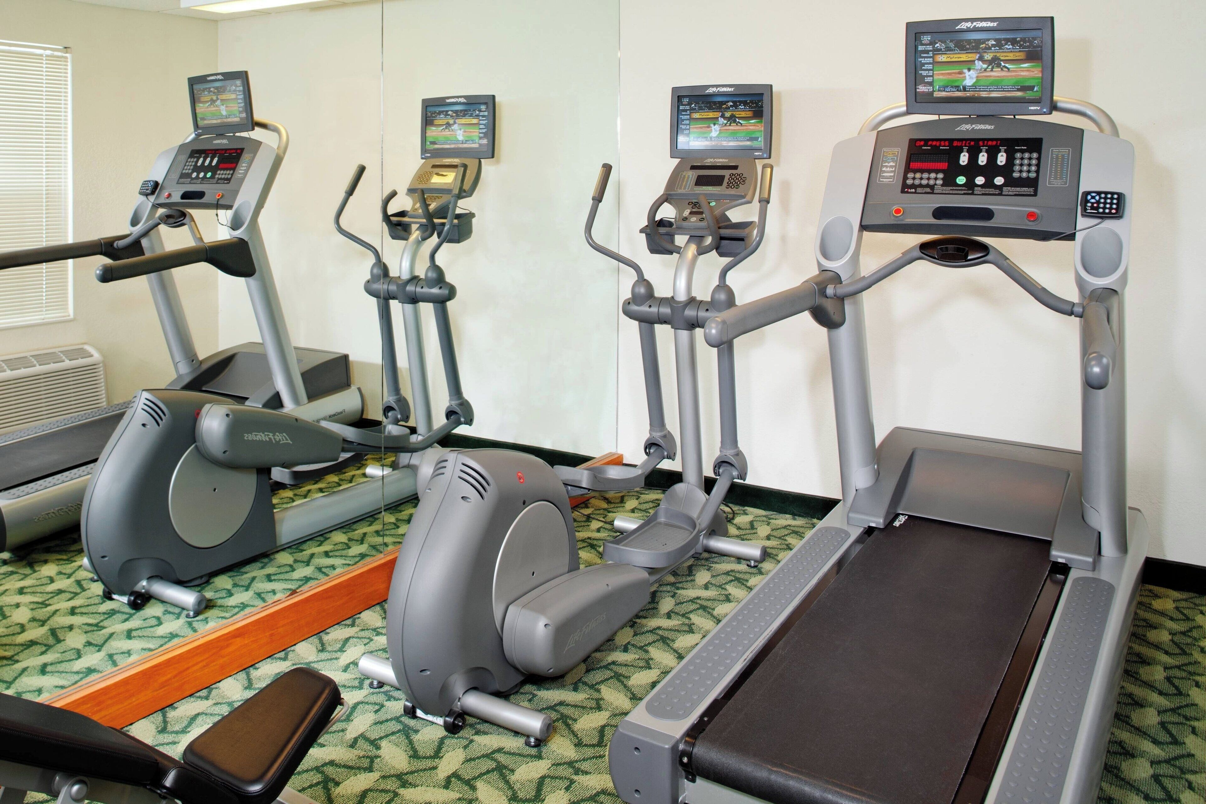 A gym with treadmills, elliptical machines, and a stationary bike.