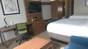 Ein Hotelzimmer mit einem Holztisch, einem Sessel, einem Bett und einem an der Wand befestigten Fernseher.