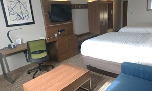 Een hotelkamer met een houten bureau, een stoel, een bed en een aan de muur bevestigde televisie.