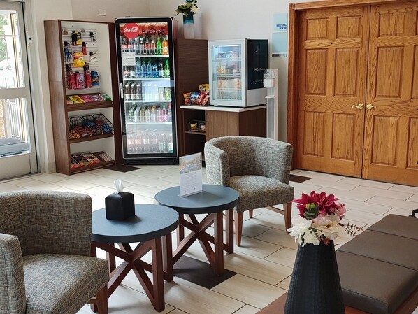 A hotel lobby with seating, a Coca-Cola refrigerator, a meeting room sign, and a wooden door. - Holiday Inn Express Murrysville - Delmont by IHG (Delmont)