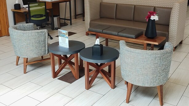 Een moderne zithoek met een bank, twee fauteuils en een kleine tafel met een bord.