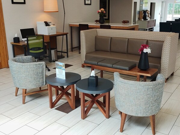 Ein stilvoller Lounge-Bereich mit einer Couch, zwei Sesseln und einem Tisch mit einem Schild.