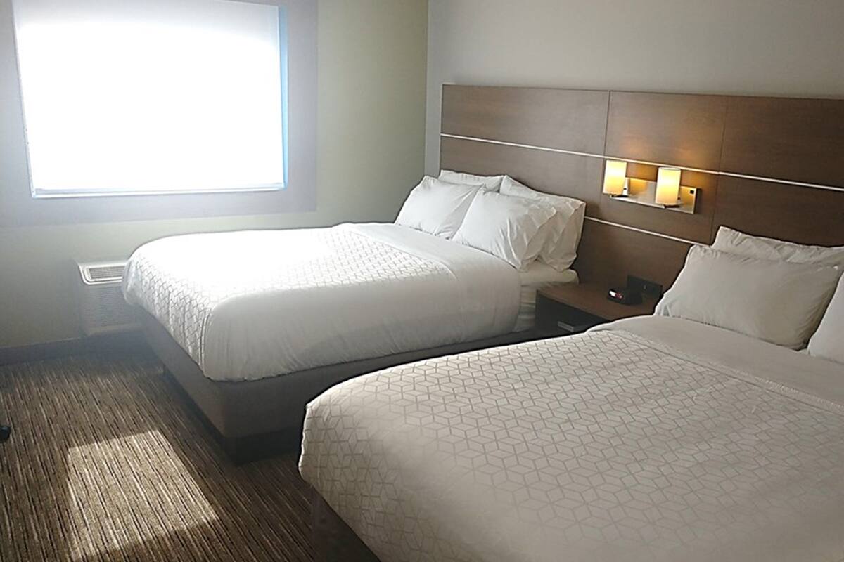 Ein Hotelzimmer mit zwei Betten, einem Nachttisch und einem Fenster mit Jalousien.