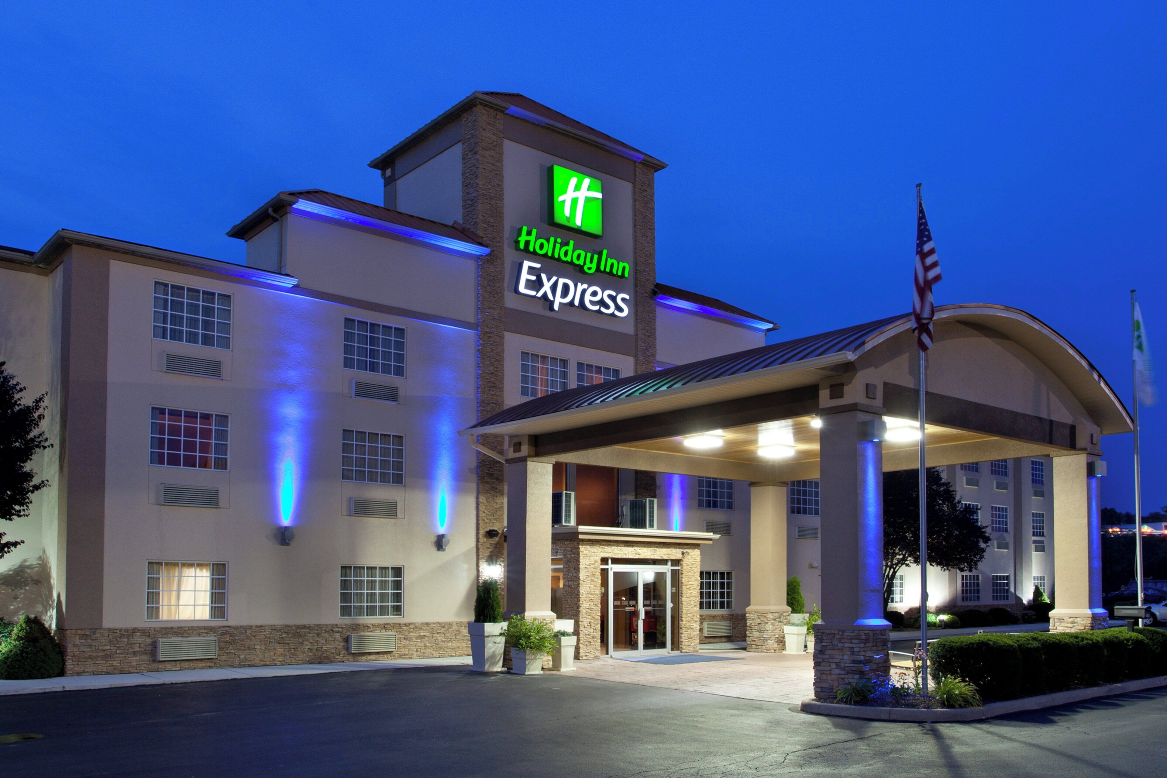 A Holiday Inn Express hotel with a covered entrance, a flagpole, and a well-lit facade.