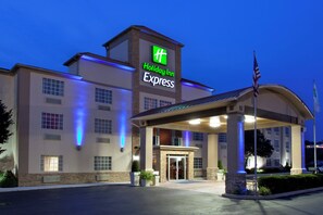 A Holiday Inn Express hotel with a covered entrance, a flagpole, and a well-lit facade.