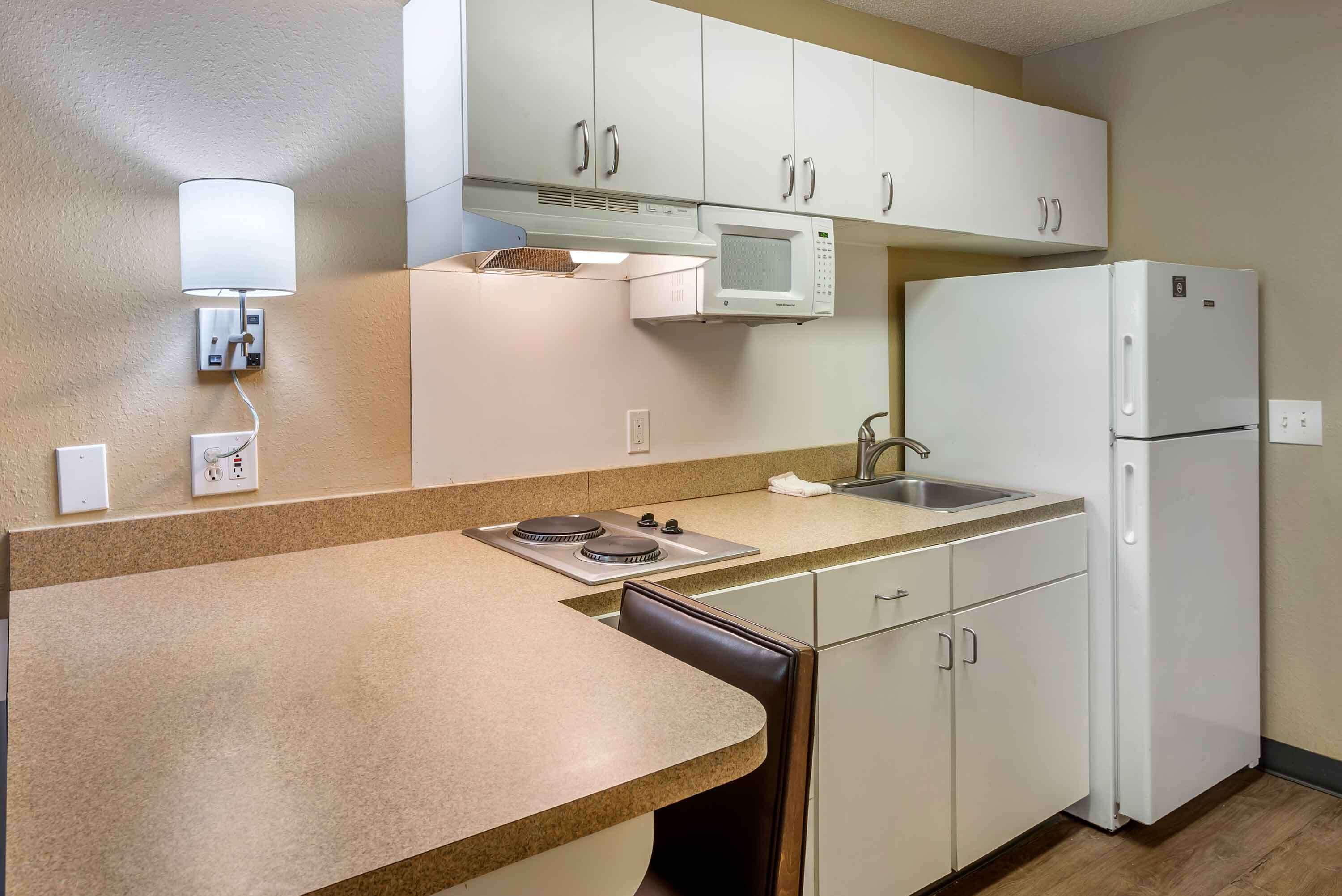 A compact kitchen with white cabinets, a microwave, a stove, and a refrigerator.