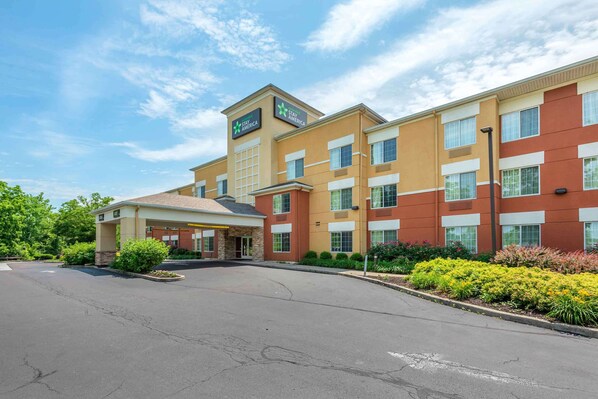 A Stay America hotel with a two-story building, a covered entrance, and a parking lot.