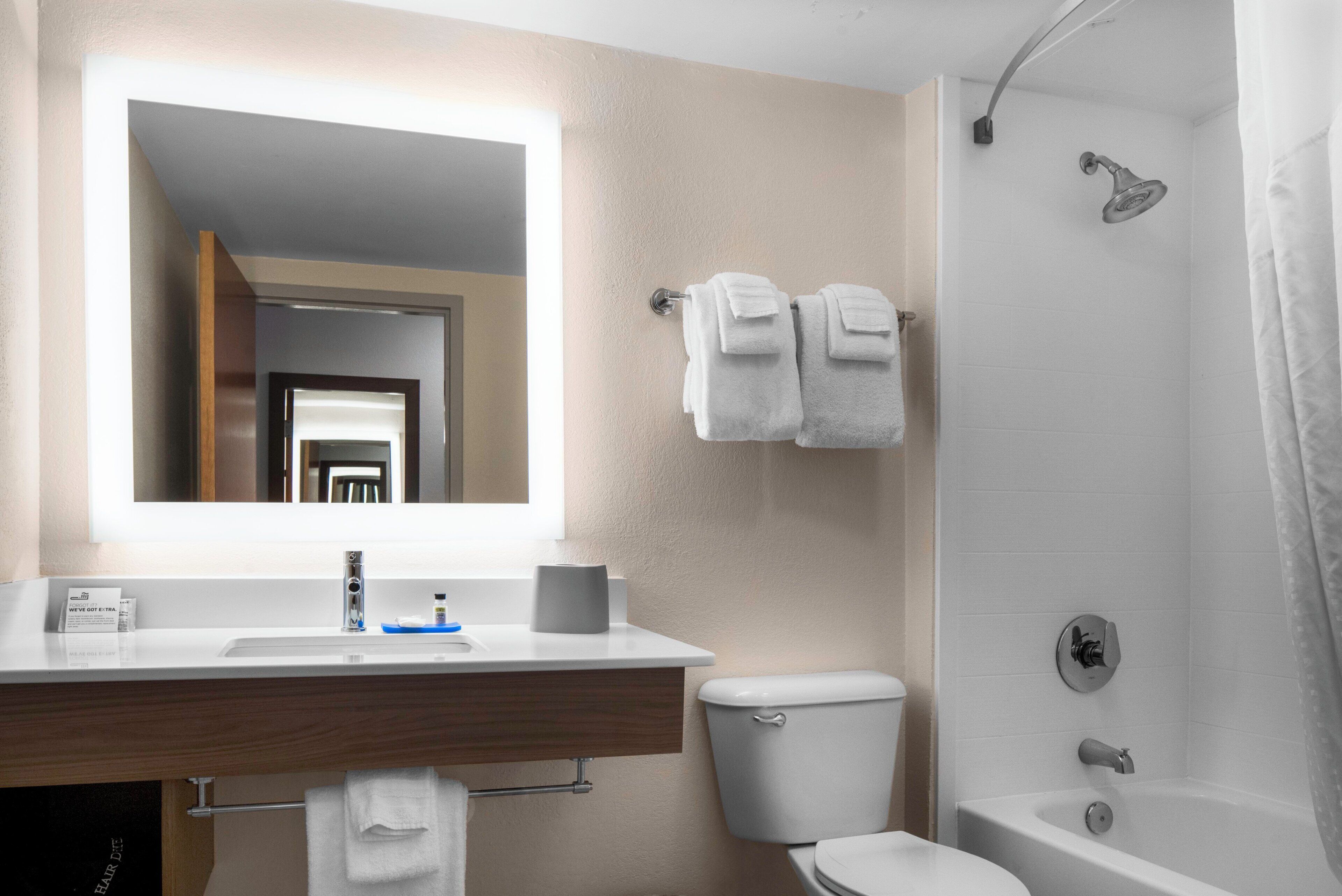 A bathroom with a sink, mirror, toilet, and shower.
