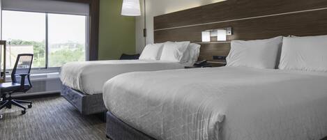 A hotel room with two beds, a desk, and a chair.