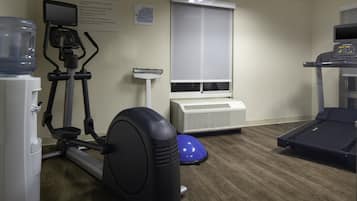 Een fitnessruimte met trainingsapparatuur, waaronder een loopband, elliptische trainer en hometrainer.