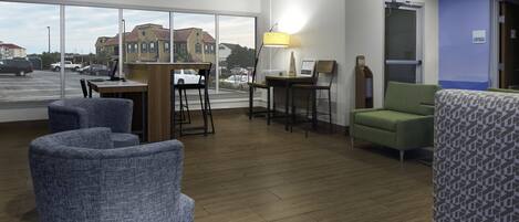 A hotel lobby with a reception desk, seating area, and large windows offering a view of the street and buildings.