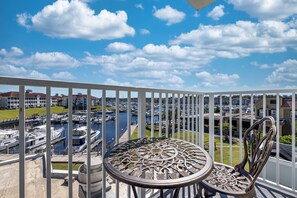 A balcony with a view of a marina, featuring a round table and two chairs. - Holiday Inn Express N.Myrtle Beach- Little River by IHG (Little River)