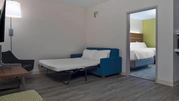Habitación de hotel pequeña con una cama individual, un escritorio, una silla y una mesita.