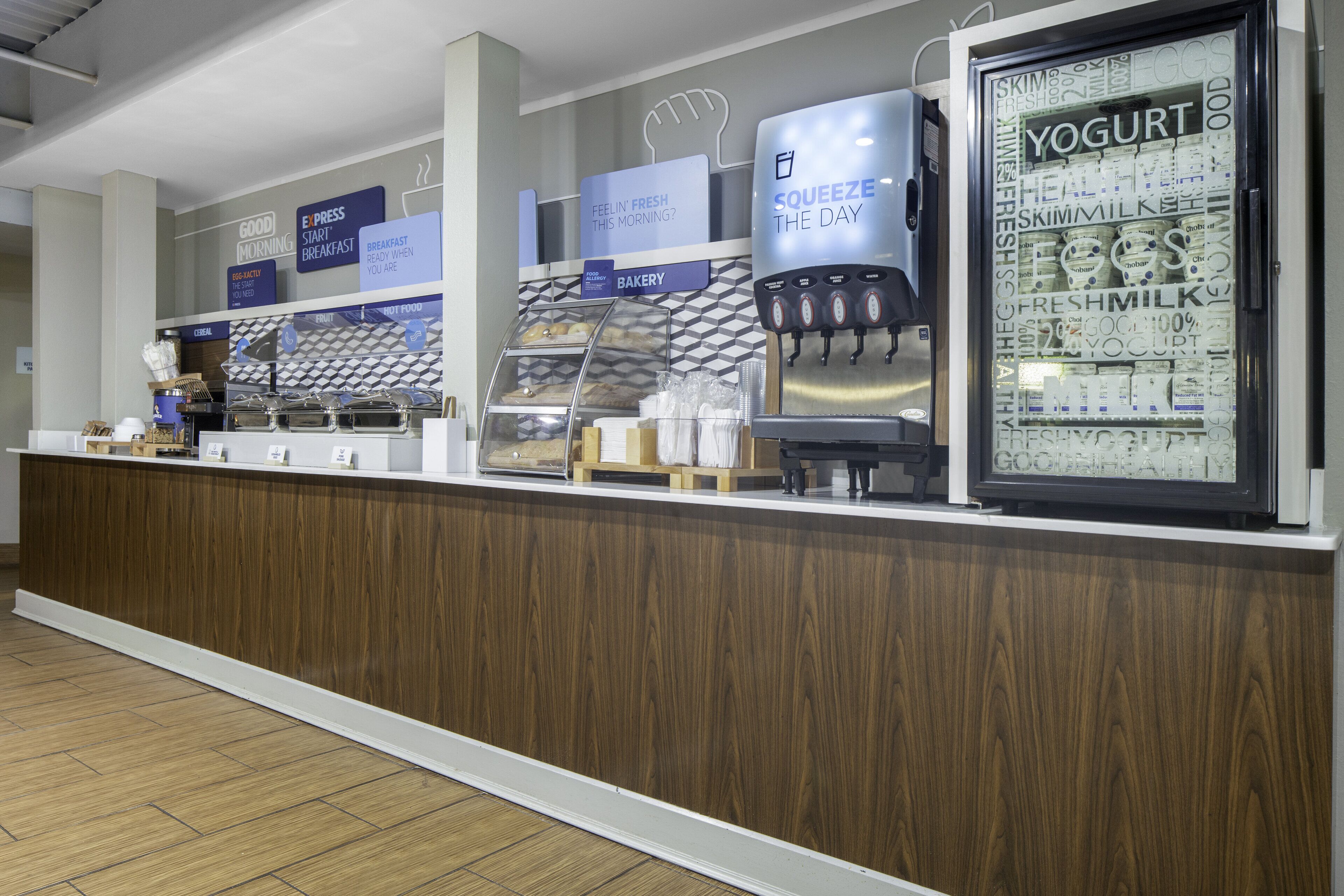 A bakery counter with a yogurt dispenser and a display of various bakery items.
