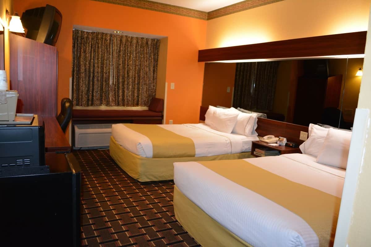 Habitació d'hotel amb dos llits, un escriptori amb telèfon i un mirall gran.