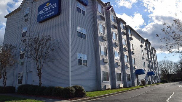 Un bâtiment de la chaîne Microtel Inn & Suites, avec une façade plate, de nombreuses fenêtres et un ciel dégagé.