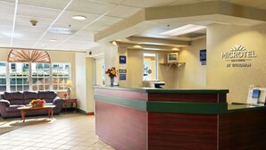 Un espace d’accueil comprenant un comptoir de réception en bois, un canapé et un vase rempli de fleurs.