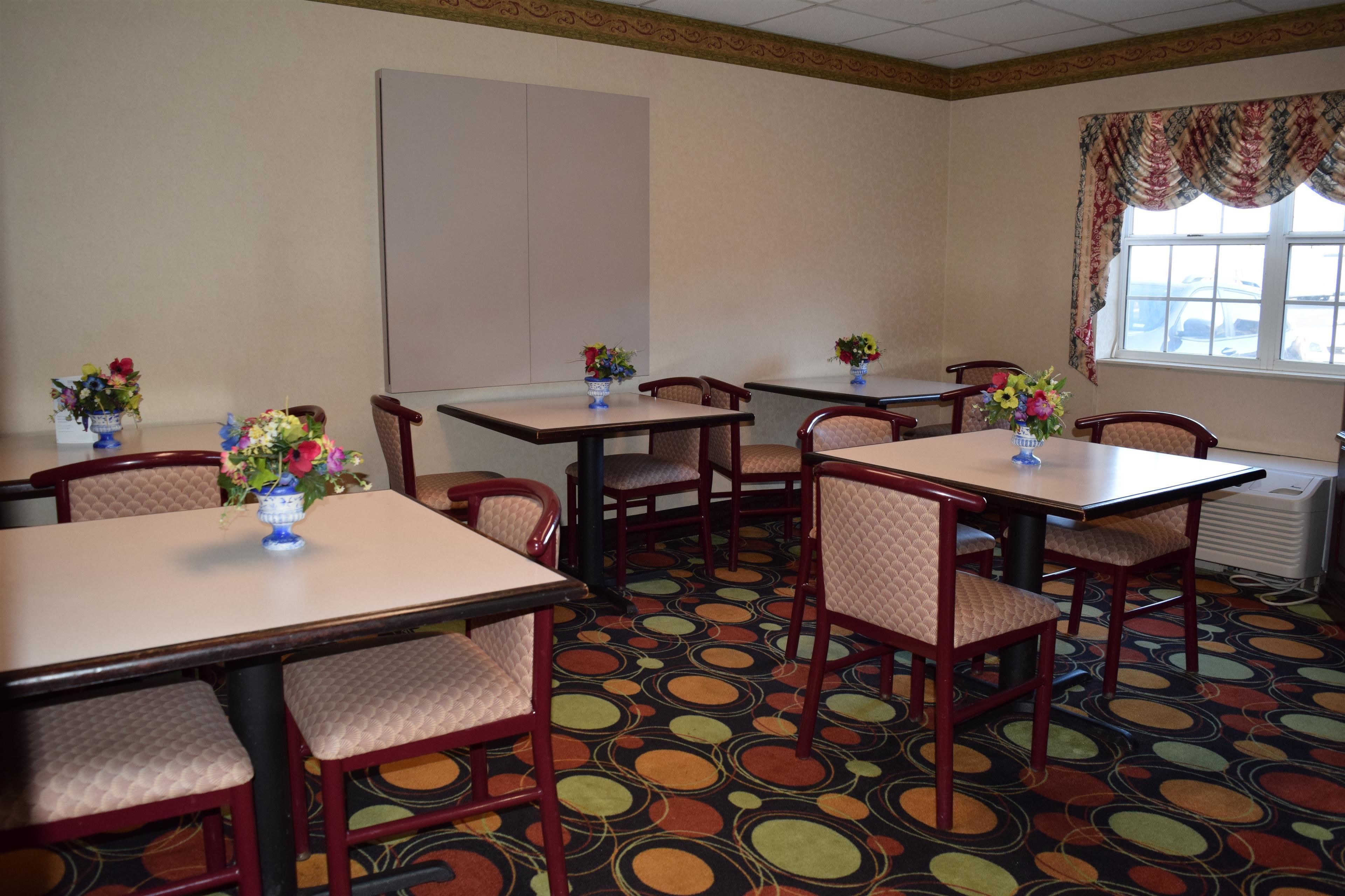 A conference room with tables and chairs, floral centerpieces, and a patterned carpet.