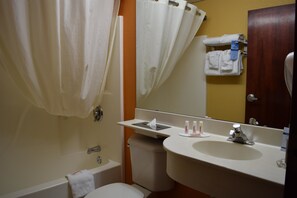 Een badkamer met een bad, toilet, wastafel en spiegel.