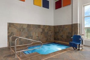 Un espace piscine avec une piscine bleue, un mur en pierre et une chaise bleue.