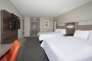Une chambre d’hôtel avec deux lits, un bureau, une télévision et une porte de salle de bain.